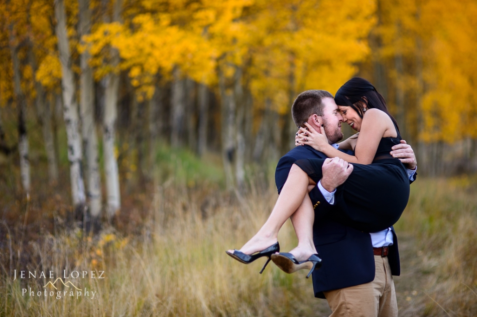 man holds woman close in arms for a kiss in colorado mountains