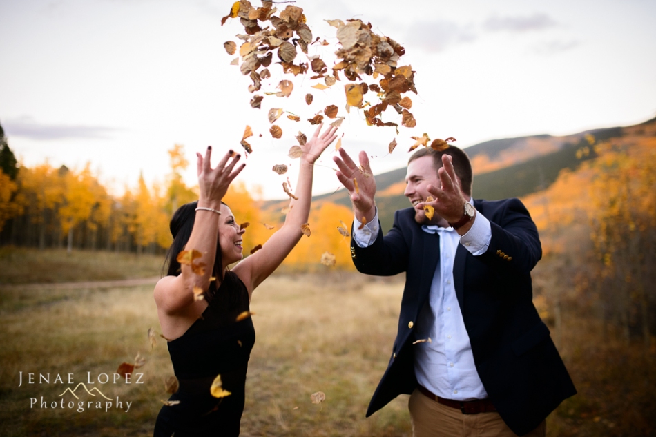 couple throws leaves in the air for engagement photo in aspen meadow
